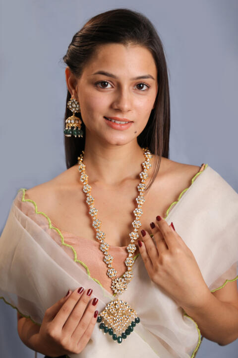Long floral necklace with pendant design and emerald jhumkis in traditional style